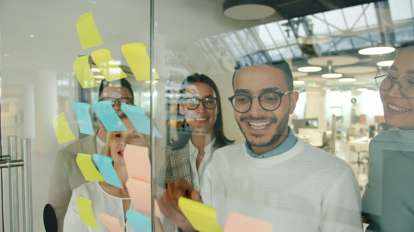 Des gens d'affaires réfléchissent à des idées sur un tableau de verre avec des notes autocollantes.